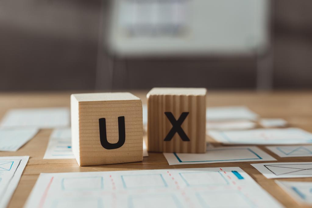 Foco seletivo de cubos com letras ux e esboços de aplicativos de designer na mesa
 - Foto, Imagem