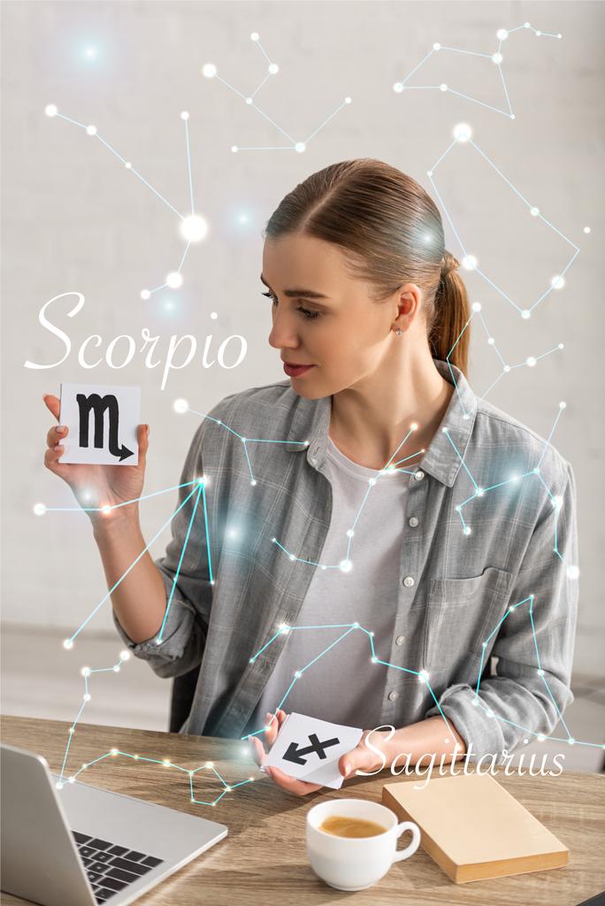 Astrologer holding cards with zodiac signs beside book, laptop and constellations  - 写真・画像