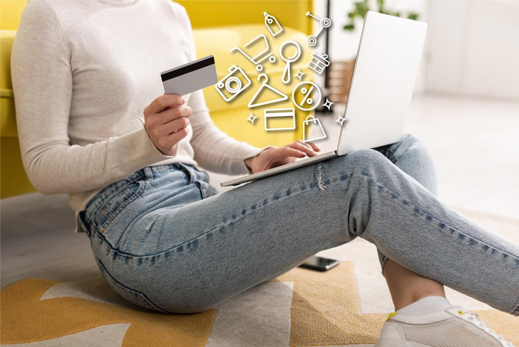 Widok upraw młodej kobiety posiadającej kartę kredytową i korzystającej z laptopa w pobliżu ilustracji - Zdjęcie, obraz