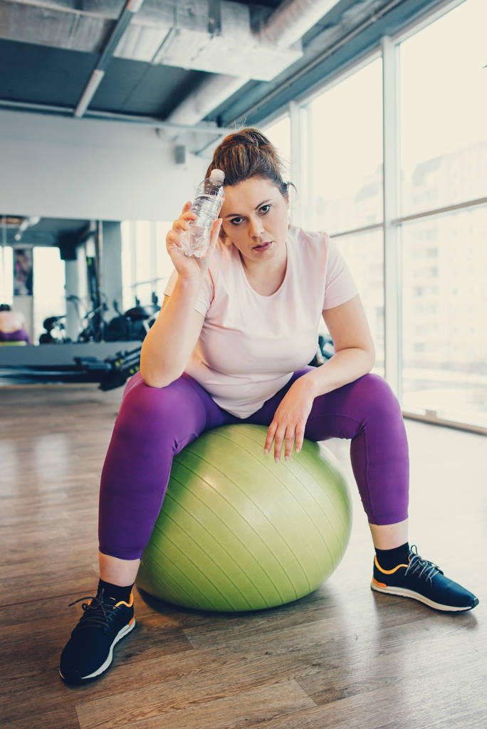 Mujer obesa se sienta en la pelota de gimnasio en el gimnasio
 - Foto, Imagen