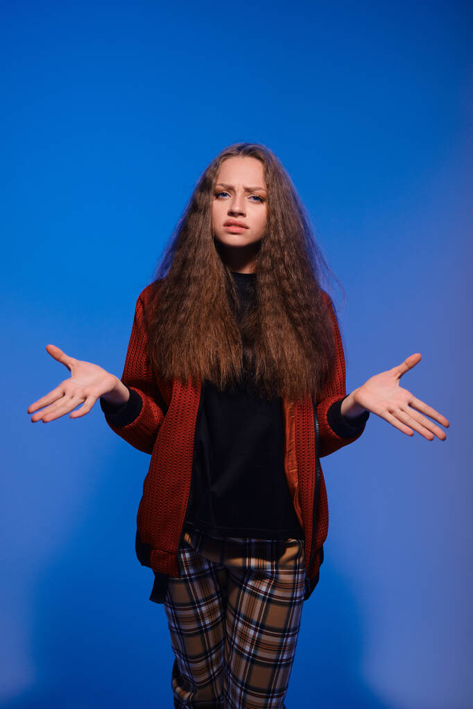 Linda adolescente posando sobre fondo azul con las manos divorciadas
 - Foto, Imagen