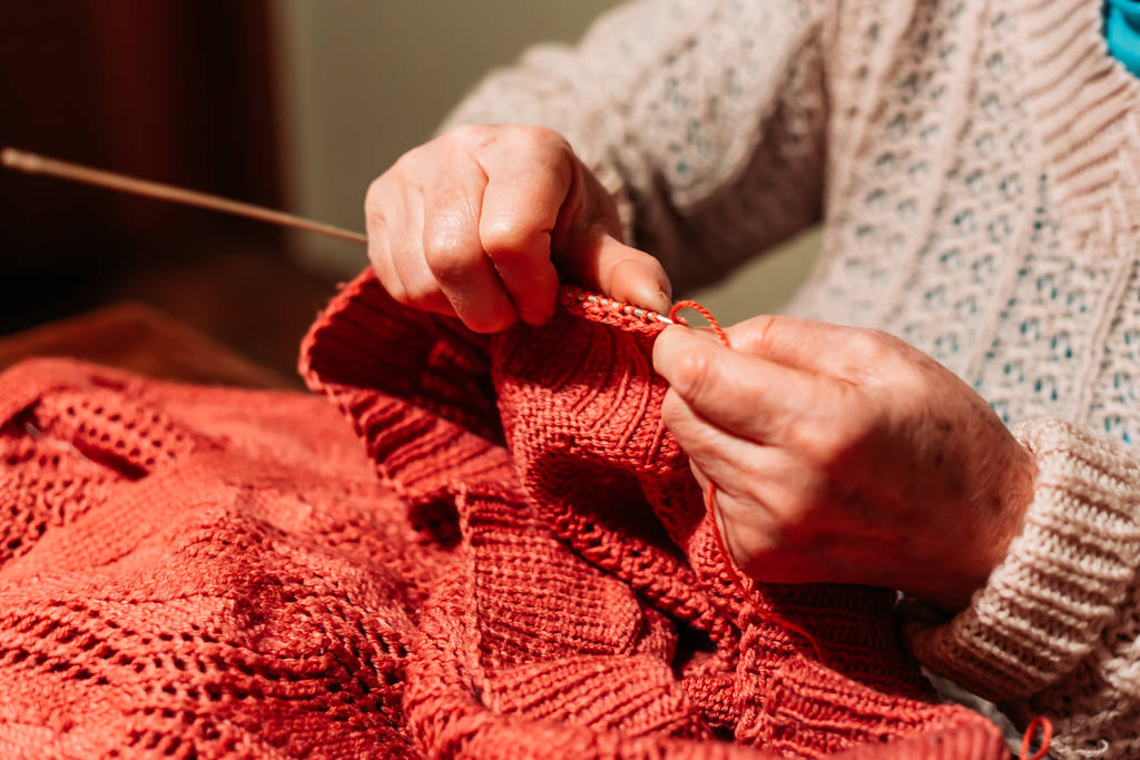 Μεγαλύτερα χέρια γυναίκας, πλέξιμο κόκκινο πουλόβερ. Χόμπι και αναψυχή - Φωτογραφία, εικόνα