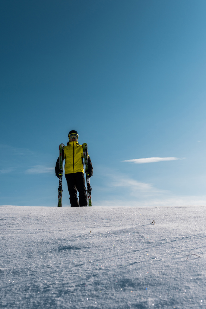 ゴーグルとヘルメットのスキーヤー雲と青い空に対してスキースティックを保持 - 写真・画像