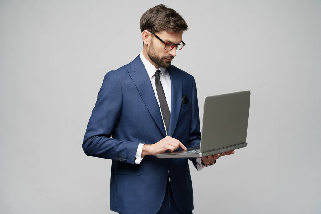 Joven hombre de negocios guapo sosteniendo una computadora portátil con pantalla en blanco
 - Foto, Imagen