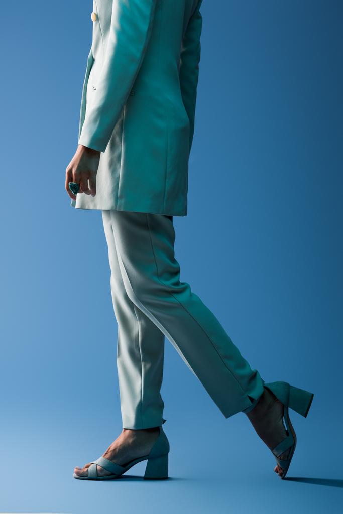 vista recortada de mujer afroamericana en traje caminando sobre fondo azul
  - Foto, imagen