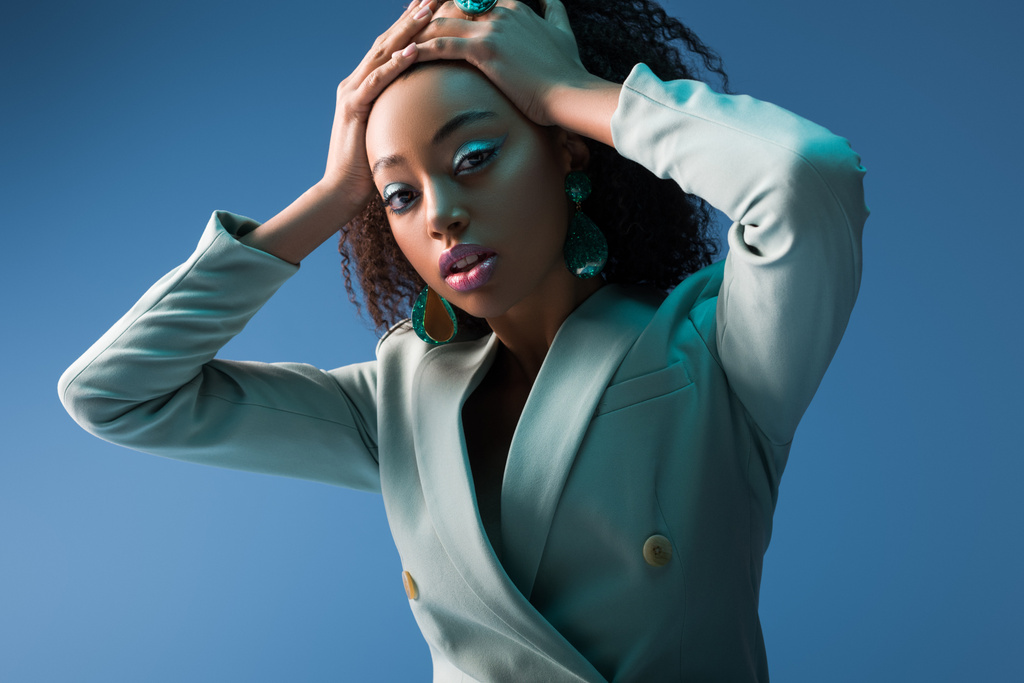 attractive african american woman with makeup in suit isolated on blue - Photo, Image