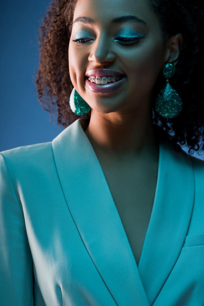 elegante donna afroamericana in bretelle sorridente isolato su blu
 - Foto, immagini