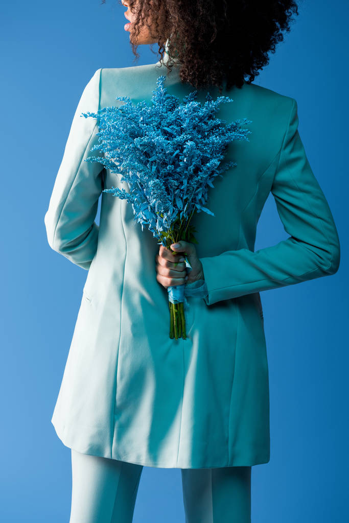 vista ritagliata di donna afro-americana tenendo bouquet isolato su blu
 - Foto, immagini