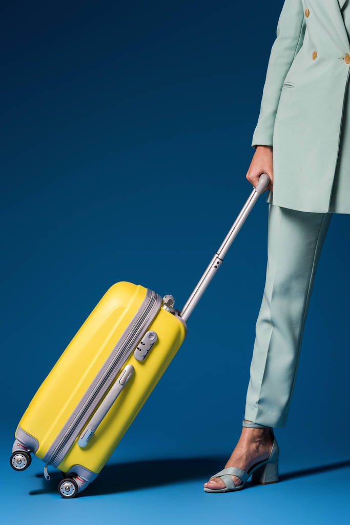 vista ritagliata della donna afro-americana che tiene borsa da viaggio su sfondo blu
  - Foto, immagini
