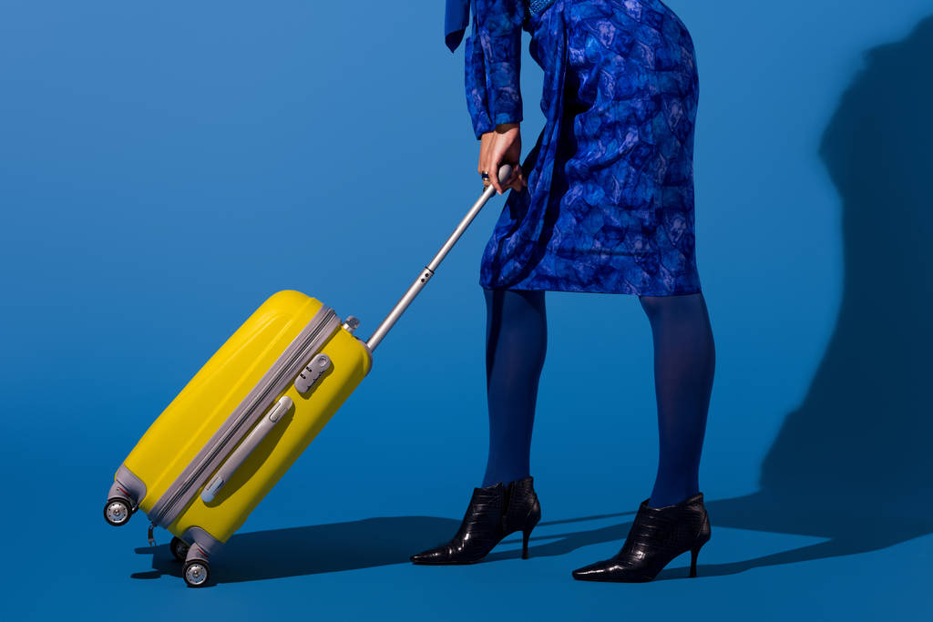 cropped view of african american woman holding travel bag on blue background  - Photo, Image