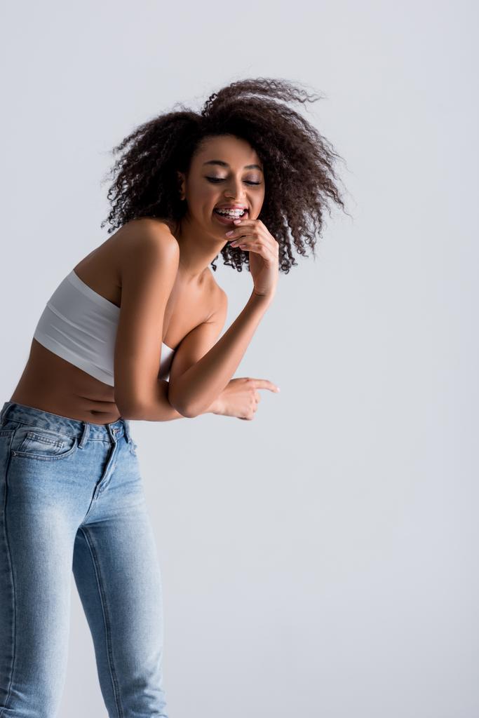 smiling african american woman in white top isolated on grey - Photo, Image