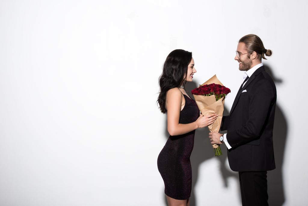 陽気なカップルがバレンタインデーに赤いバラの花束を持って - 写真・画像