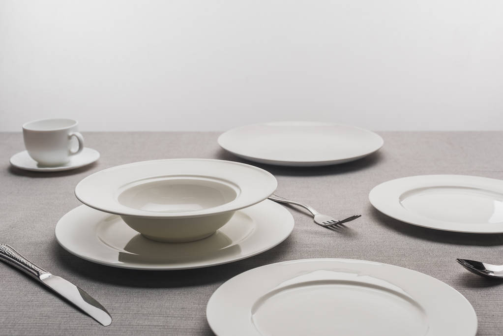 Empty tableware with coffee cup on tablecloth on gey background - Photo, Image