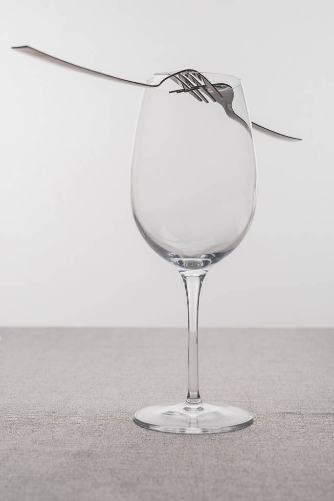 灰色で隔離されたテーブルクロス上の空のワイングラスのフォーク - 写真・画像