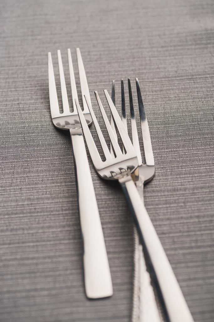 Enfoque selectivo de tenedores brillantes en tela de lino gris
  - Foto, imagen