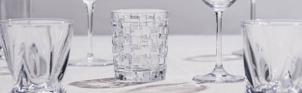 Foto panorámica de vasos vacíos sobre tela blanca sobre fondo gris
 - Foto, Imagen