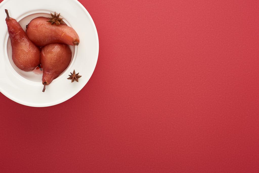 ylhäältä näkymä herkullinen päärynä viiniä anis lautasella punaisella pohjalla
 - Valokuva, kuva