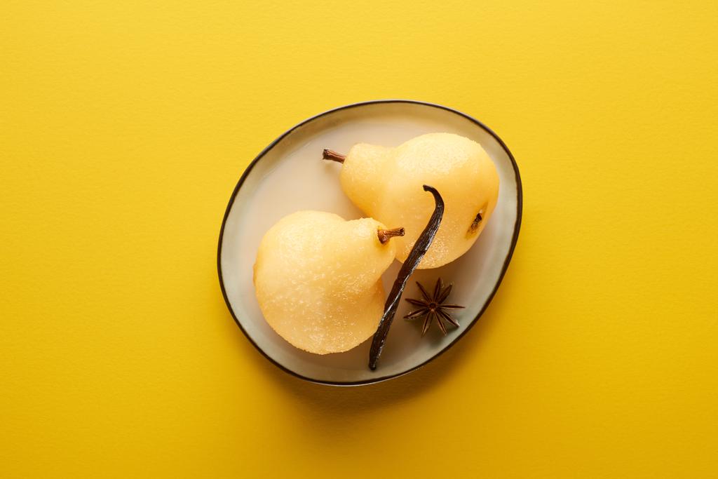 vista superior de la deliciosa pera en vino con anís en plato sobre fondo amarillo
 - Foto, Imagen