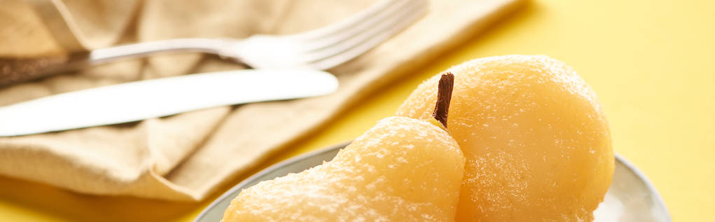 selective focus of delicious pear in wine on plate near napkin and cutlery, panoramic shot - Photo, Image