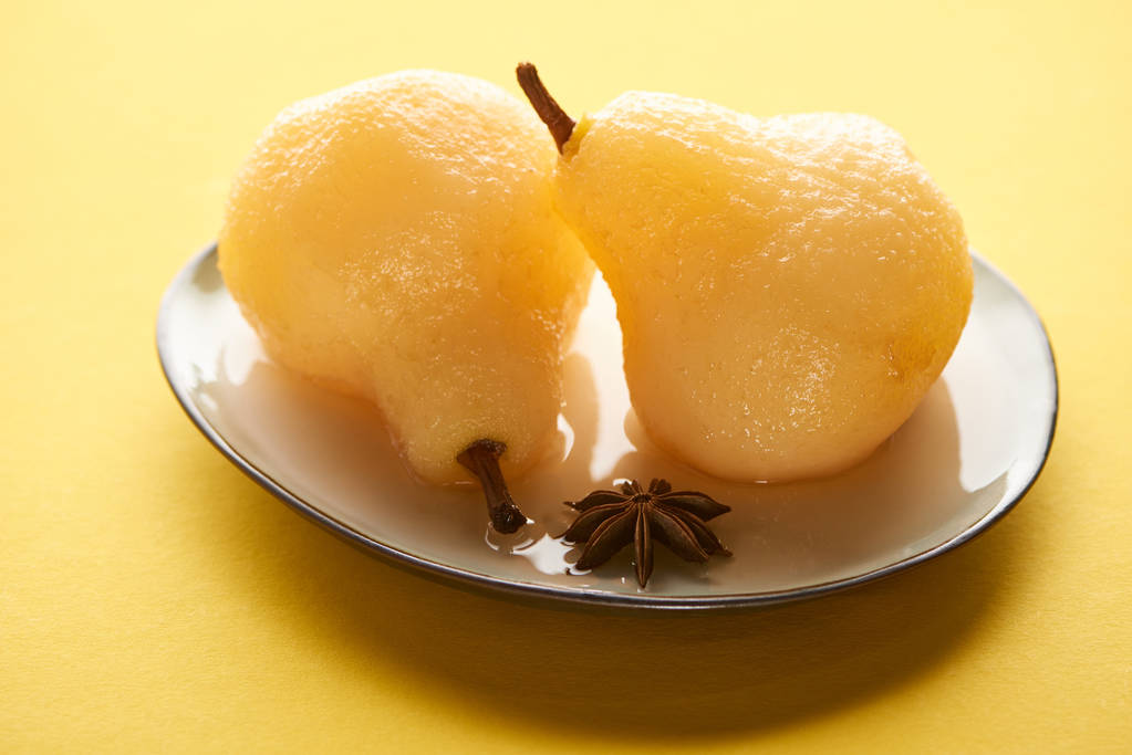 delicioso pera en vino en plato con anís sobre fondo amarillo
 - Foto, imagen
