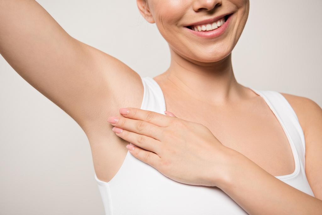 partial view of smiling woman applying deodorant on underarm isolated on grey - Photo, Image