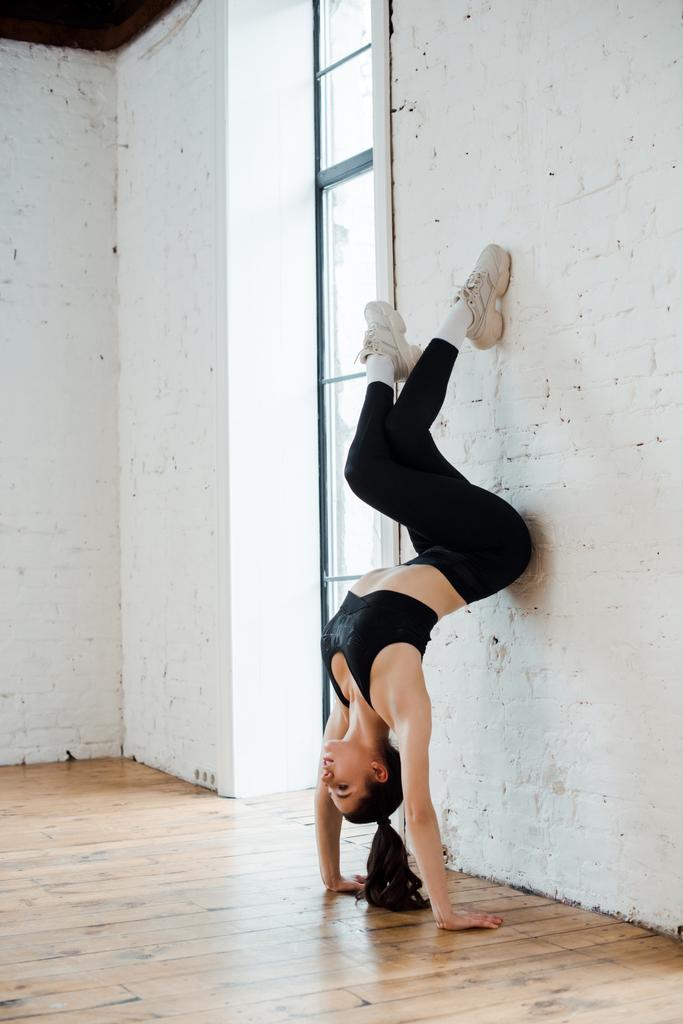 jeune femme faisant handstand près de mur de briques dans le studio de danse
  - Photo, image