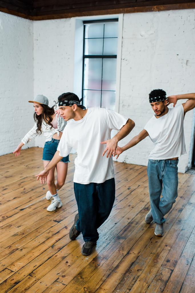 dançarinos multiculturais bonitos em headbands e menina atraente em cap dançando hip-hop
  - Foto, Imagem