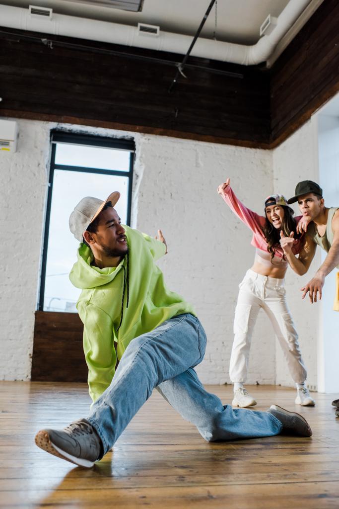 selectieve focus van Afrikaanse Amerikaanse danser breakdancing in de buurt van emotionele man en meisje - Foto, afbeelding