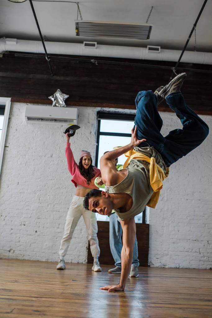 selective focus of man breakdancing near excited multicultural dancers  - 写真・画像