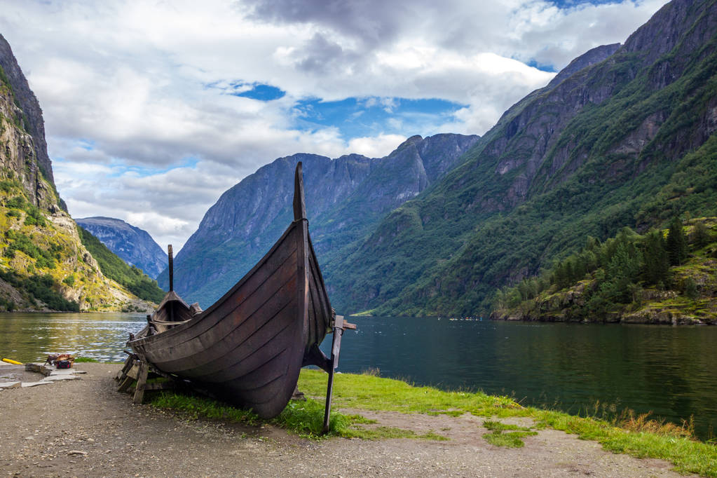 clouds over viking boat and village on Naeroyfjord in Gudvangen in Norway - Photo, Image