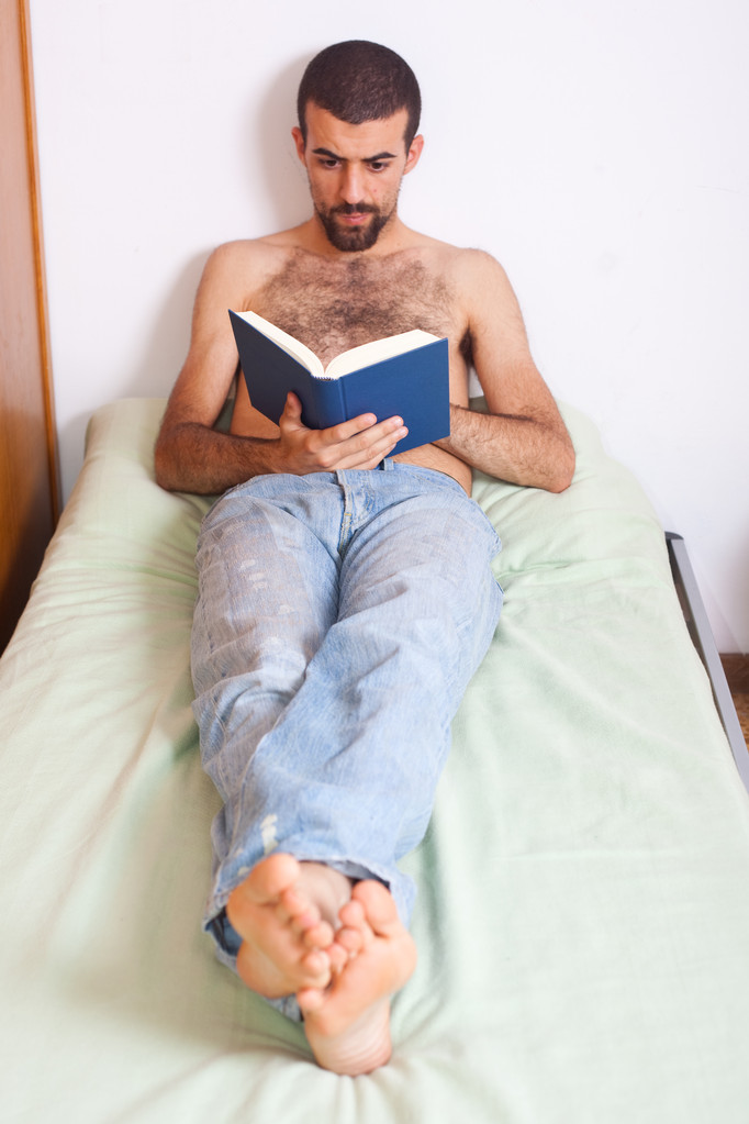 άνθρωπος, διαβάζοντας ένα βιβλίο στο κρεβάτι - Φωτογραφία, εικόνα