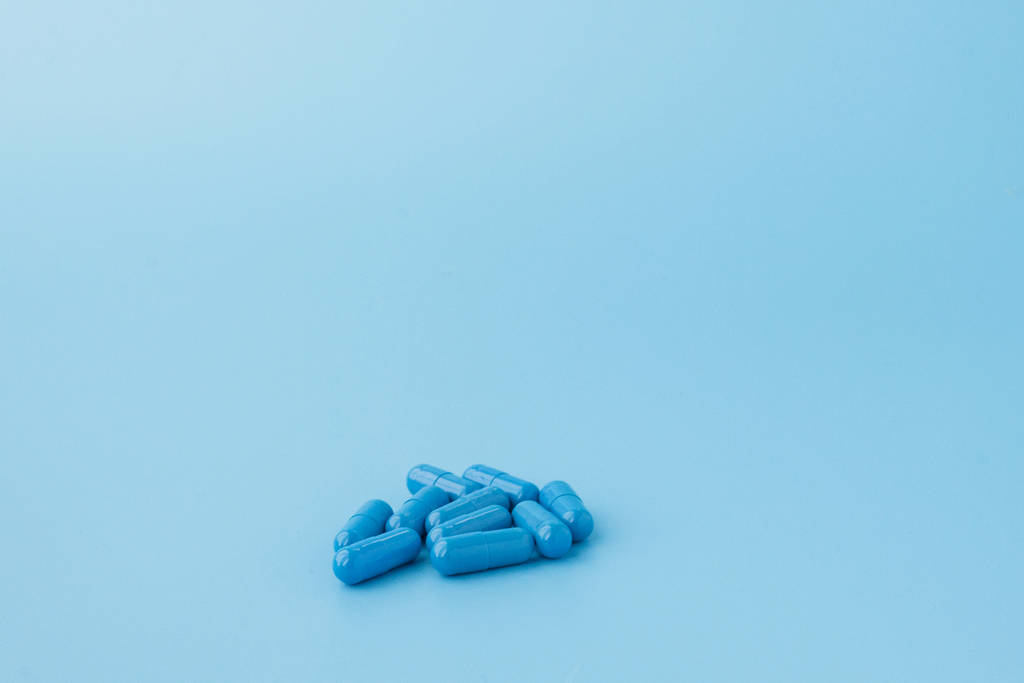 Niebieskie kapsułki, tabletki na niebieskim tle. Witaminy, odżywcze - Zdjęcie, obraz