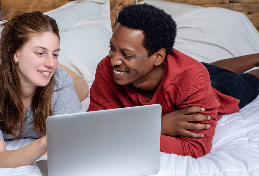 Evde bir yatakta laptop kullanarak genç çift. - Fotoğraf, Görsel