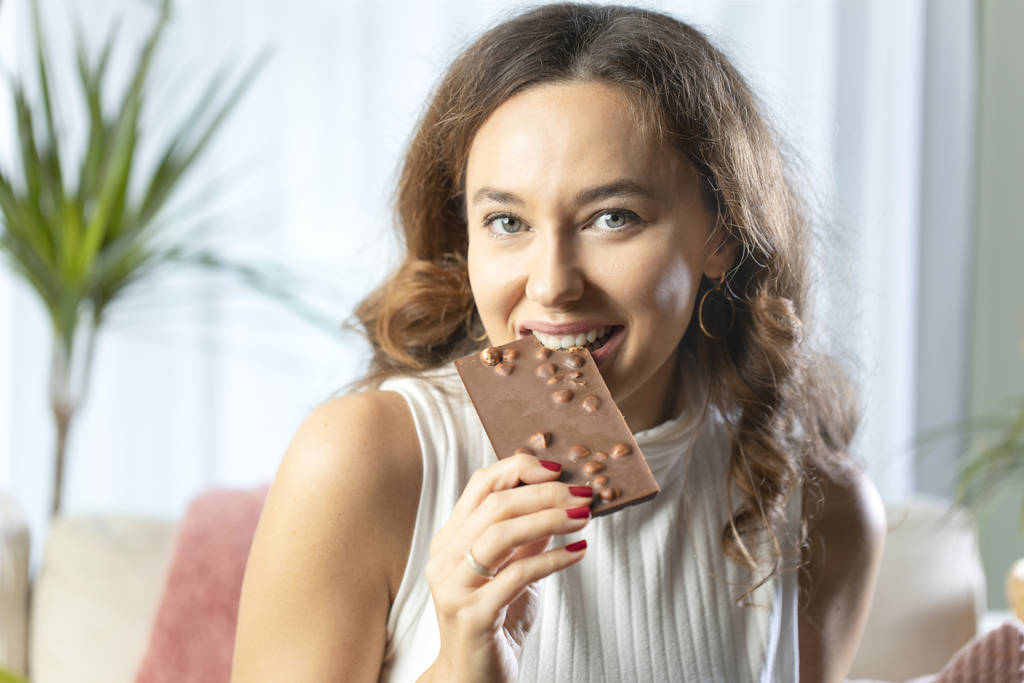 Młoda kobieta cieszy się batonikiem czekoladowym w Hom - Zdjęcie, obraz
