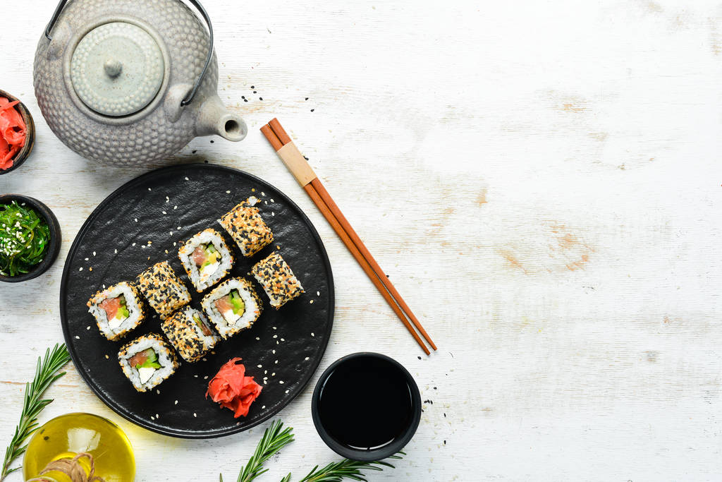 Sushi-Rolle mit Sesam, Philadelphia-Käse, Lachs, Avocado. Traditionelle japanische Küche. Ansicht von oben. rustikaler Stil. - Foto, Bild