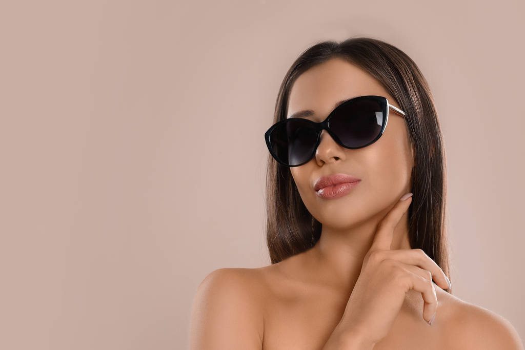 Beautiful young woman wearing sunglasses on beige background. Space for text - Fotoğraf, Görsel