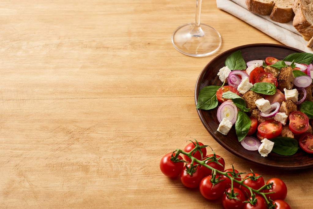 köstliche italienische Gemüsesalat Panzanella serviert auf Teller auf Holztisch in der Nähe von frischen Tomaten, Brot - Foto, Bild