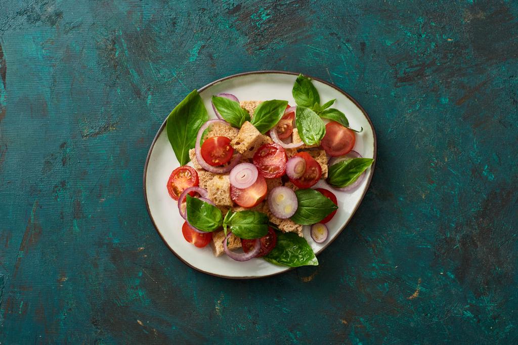 vista superior de la deliciosa ensalada de verduras italiana panzanella servido en el plato en la superficie verde texturizada
 - Foto, imagen
