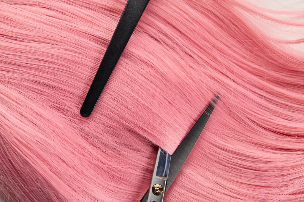 Κάτοψη του κλιπ και ψαλίδι σε χρωματιστά ροζ μαλλιά σε λευκό φόντο - Φωτογραφία, εικόνα