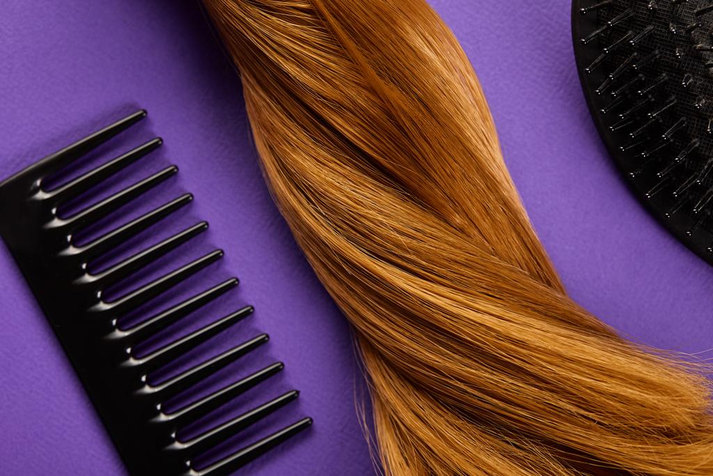 Top view of brown hair with comb and hairbrush on purple background - Photo, Image