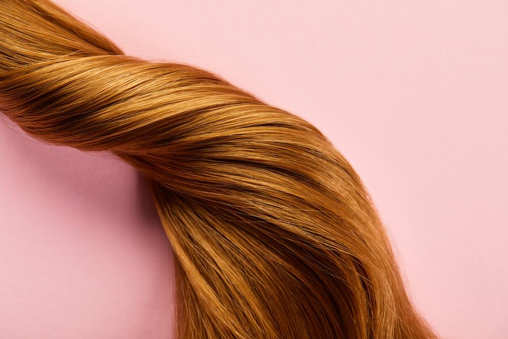 Draufsicht der verdrehten braunen Haare auf rosa Hintergrund - Foto, Bild