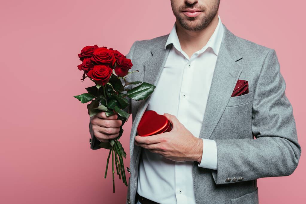 καλλιεργημένη άποψη του ανθρώπου κρατώντας κουτί δώρου καρδιά και μπουκέτο τριαντάφυλλα για την ημέρα του Αγίου Βαλεντίνου, απομονώνονται σε ροζ - Φωτογραφία, εικόνα
