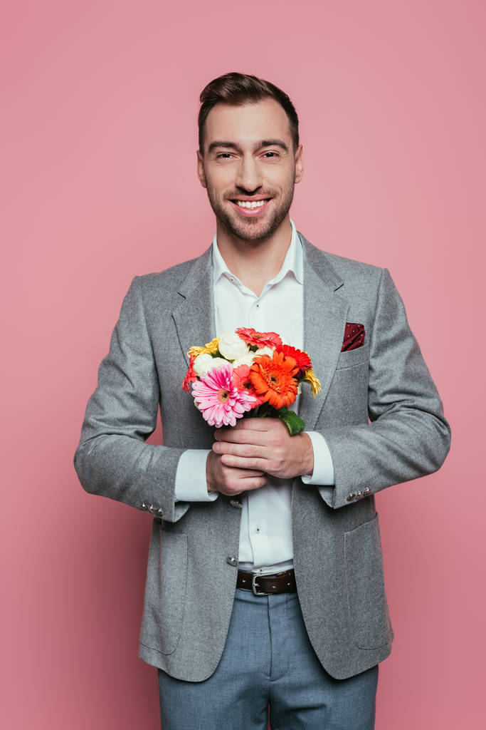 mosolygós férfi kezében csokor virág, elszigetelt rózsaszín - Fotó, kép