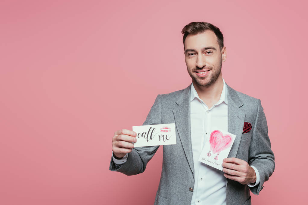 bell'uomo barbuto con in mano due biglietti da visita di San Valentino, isolato su rosa
 - Foto, immagini