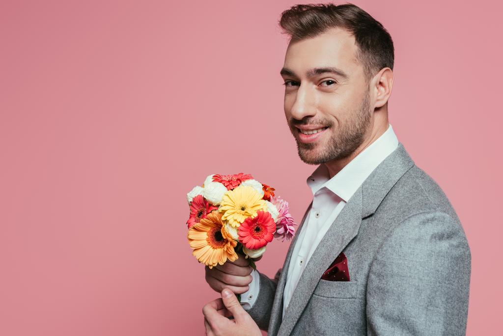 bearded smiling man holding bouquet of flowers, isolated on pink - Photo, Image