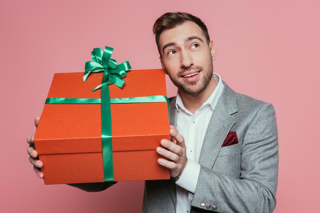 mosolygós férfi öltönyben kezében nagy ajándék doboz, elszigetelt rózsaszín - Fotó, kép