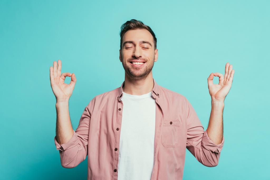 χαρούμενος άνθρωπος με κλειστά μάτια δείχνει om χειρονομία, απομονώνονται σε μπλε - Φωτογραφία, εικόνα