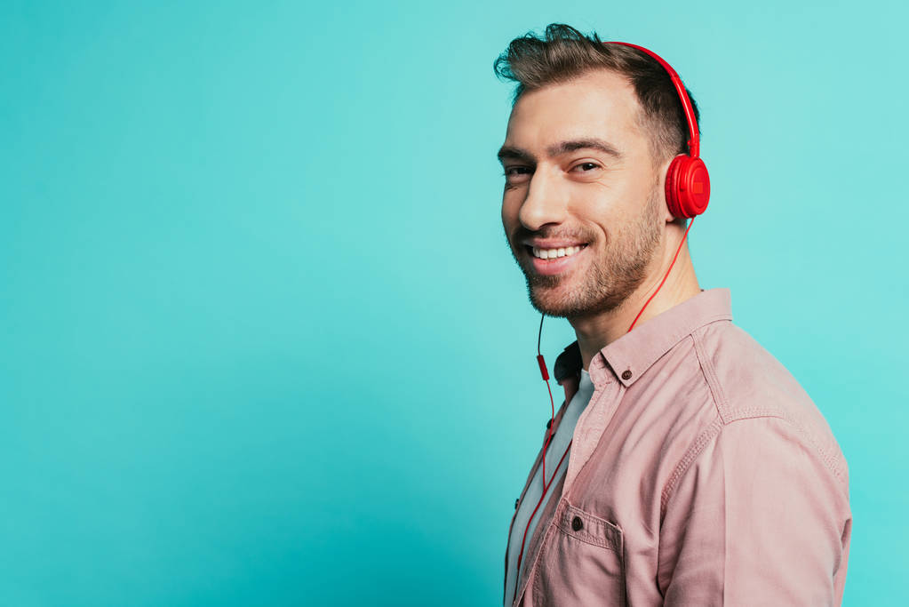 uśmiechnięty brodaty mężczyzna słuchający muzyki ze słuchawkami, odizolowany na niebiesko - Zdjęcie, obraz