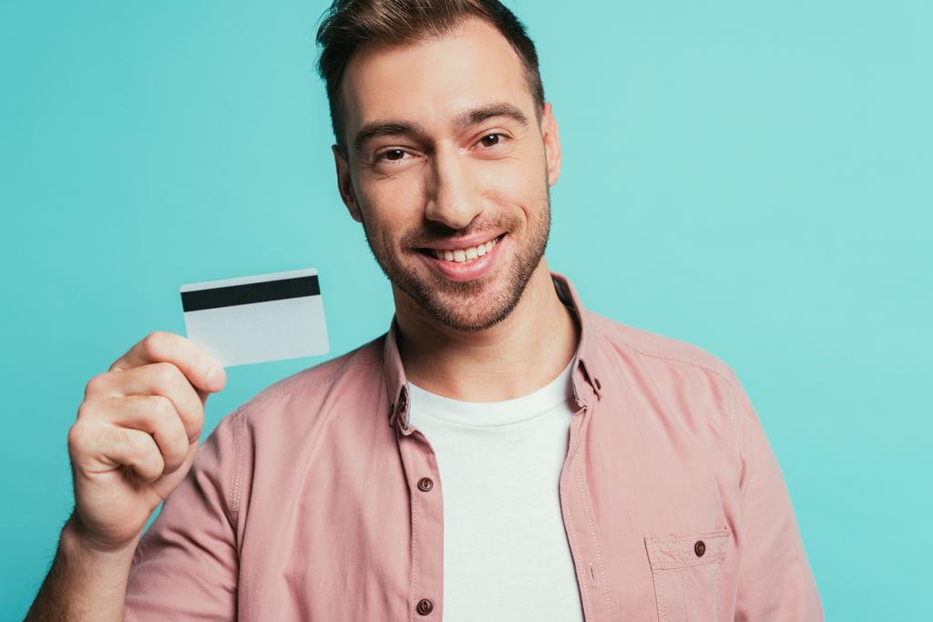 happy bearded man holding credit card, isolated on blue - Photo, Image