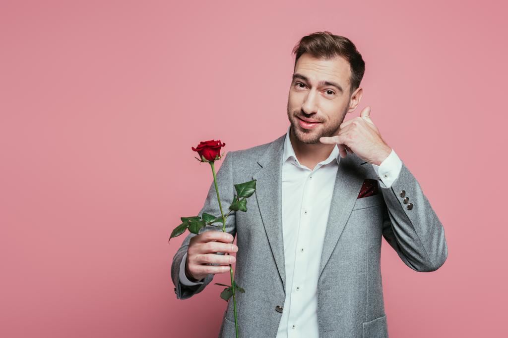 bearded man in suit holding rose flower and showing call me gesture, isolated on pink - Photo, Image